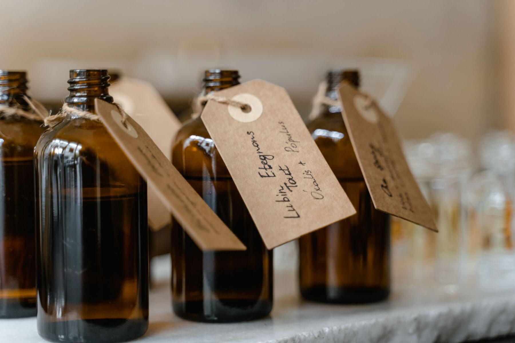 Amber glass bottles with handwritten kraft paper tags tied with twine on a sunlit shelf